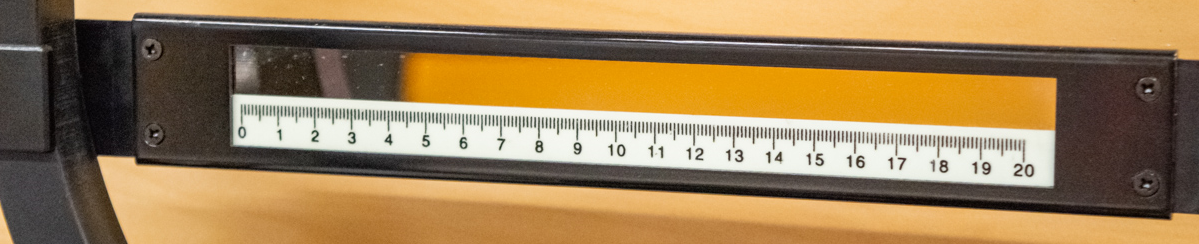 Mirror and ruler, movable to line up and bisect the circular electron beam.